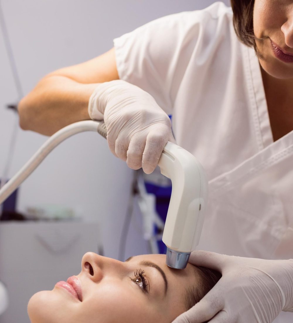Doctor giving cosmetic treatment to female patient at clinic